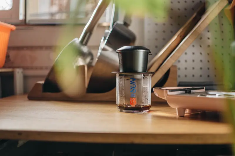 A cozy kitchen featuring a coffee maker and kitchen tools on a wooden counter, emphasizing a warm home vibe