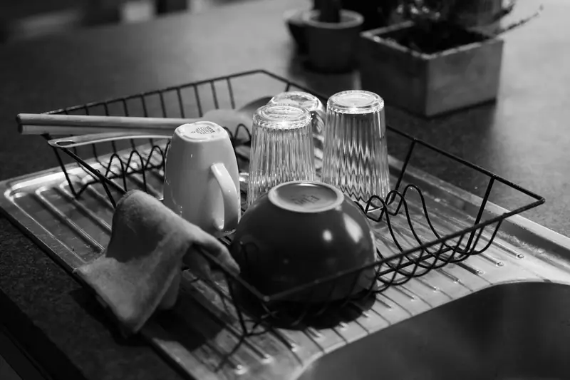 Black and white shot of a dish rack with glass and ceramic kitchenware